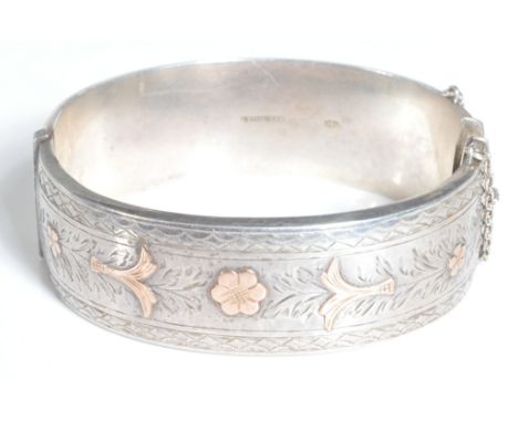 An early 20th century continental hallmarked sterling silver bracelet bangle having yellow metal floral embellishments with s