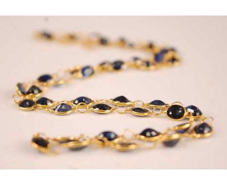 A contemporary yellow metal sapphire set necklace, arranged as 42 oval cut sapphires, each weighing approx 0.2 carats, on fin