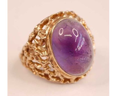 A 9ct yellow gold amethyst dress ring, featuring an oval cabochon cut amethyst in a bezel setting, with textured openwork sho