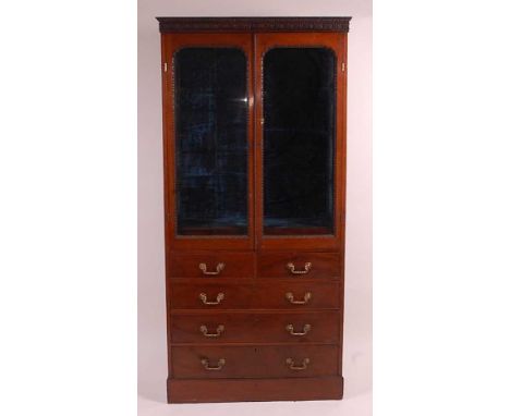 A Victorian mahogany wall cabinet, having a blind carved frieze over twin glazed doors, enclosing velvet lined interior and t