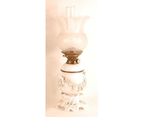 An early 20th century continental porcelain blanc-de-chine oil lamp, having clear acid etched shade, the font with applied le