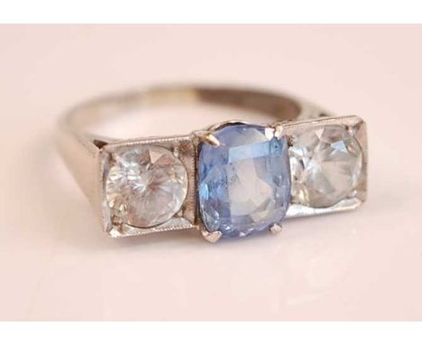 A white metal, sapphire and zircon three-stone ring, featuring a centre oval faceted sapphire flanked to either side by a rou