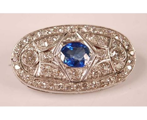 A white metal Art Deco style sapphire and diamond lozenge shaped panel brooch, featuring a centre oval faceted sapphire surro