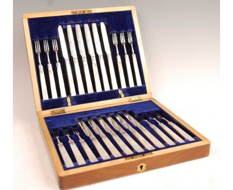 An Edwardian walnut fitted canteen containing twelve place setting of mother of pearl handled and silver-bladed cake knives a
