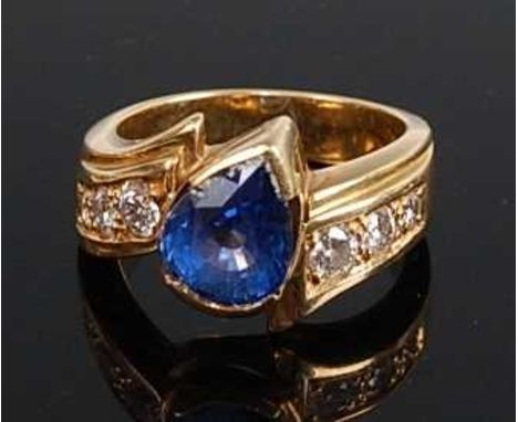 An 18ct yellow gold, tanzanite and diamond crossover style ring, featuring a pear cut tanzanite in a semi-bezel setting with 