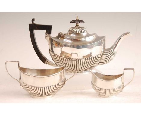 A George V bachelors three-piece silver tea set, comprising teapot, twin handled sugar and cream, each of half-reeded oval fo
