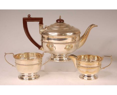 A George V silver three-piece tea set, comprising teapot, twin handled sugar and cream, each of circular form with single bea