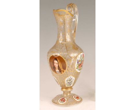 A 19th century Bohemian overlaid glass pedestal ewer, the panels polychrome decorated with opposing portrait of a young woman