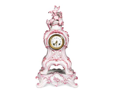 A French porcelain Rococo style mantel clock on stand, late 19th century, with pink painted decoration, the floral crest abov