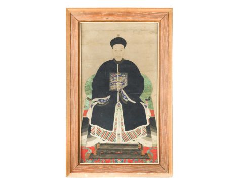 A late Qing Dynasty Chinese ancestor portrait of a male court official, wearing indigo robes, with a phoenix rank badge, seat