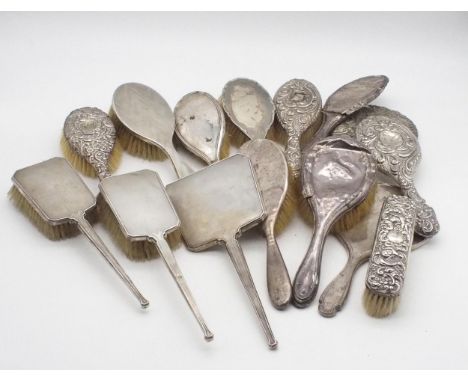 A collection of silver dressing table sets including a three piece example, the bodies with engine turned decoration, by Will