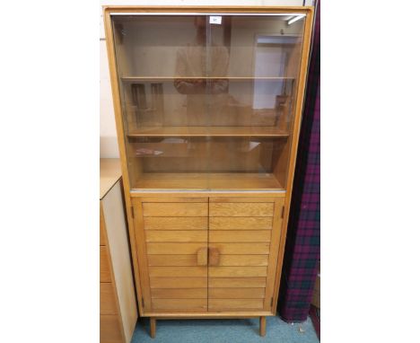 A mid 20th century blonde oak Minty Oxford bookcase with glazed sliding doors over pair of panel doors on shaped supports, 15