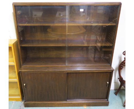 A mid 20th century stained teak glazed bookcase with pair of glass sliding doors over pair of sliding panel doors, 142cm high