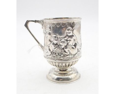 An Edwardian silver christening mug, of cylindrical form, with cast and embossed decoration of cherubs playing, on a footed a