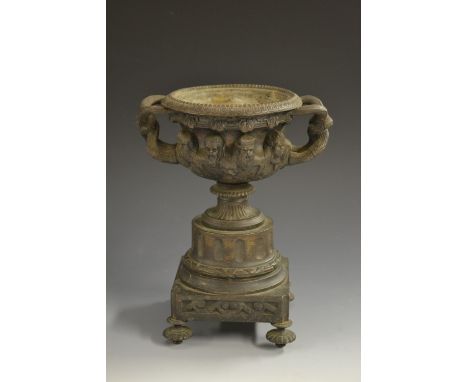 A 19th century dark patinated bronze urn, cast after the antique with bearded masks, entwined branch handles, square base, kn
