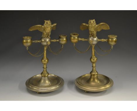 A pair of 19th century silvered and gilt novelty candelabra, each crested by an owl  perched on a ball, the hinged head enclo