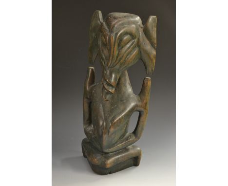 Tribal Art - a hardwood fertility figure, kneeling, stylised features with twisted nose and mouth, possibly Indonesian, remai