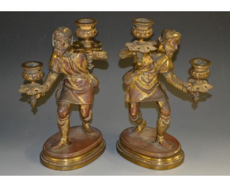 A pair of 19th century figural two-light candelabra, each cast as a Medieval vagabond, creeping through the night, a sconce i