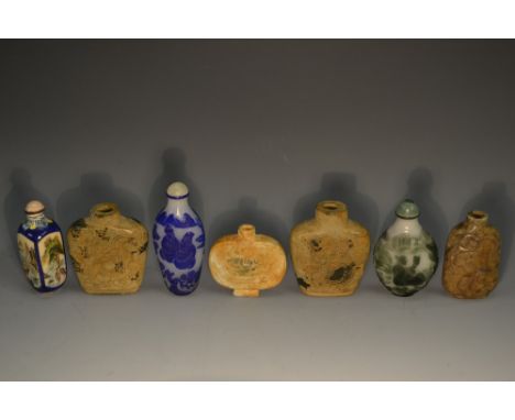 A Chinese rounded rectangular enamel snuff bottle, painted with stylized landscapes in shaped reserves, lotus-capped shoulder