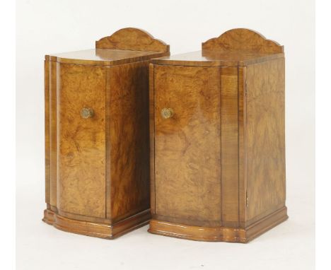 A pair of Art Deco walnut pot cupboards,of shaped cloud design, each opening to reveal a drawer and shelf with Bakelite flowe