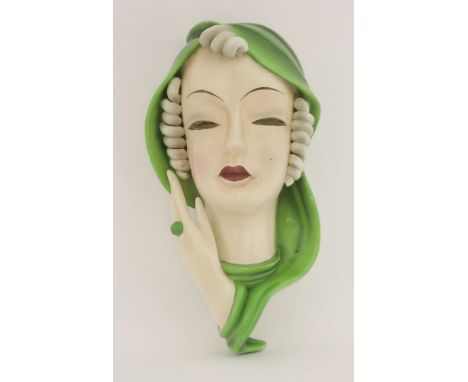 A Goldscheider pottery wall mask,modelled as a lady with a green cape, inscribed 'F.D.', with printed Goldscheider label and 