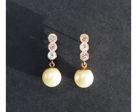 A pair of pearl and diamond earrings, set with three round old cut diamonds above a suspended pearl, to a yellow metal settin