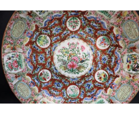 A Cantonese porcelain charger, the centre painted with butterflies and garden flowers with similar vignettes to the rim, amon