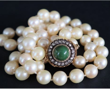A pearl necklace set with fifty nine large regular pearls to a diamond and cabochon set yellow metal clasp, 61.5cm long, pear