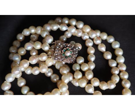 A three strand pearl necklace / choker, set with round regular pearls to a pearl and cabochon emerald clasp set in 9ct yellow