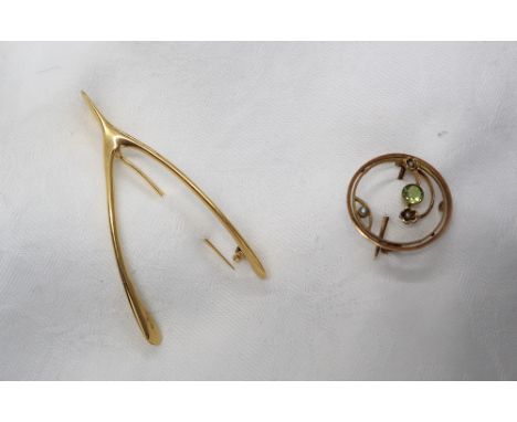 A yellow metal wishbone brooch, together with a 9ct yellow gold peridot and seed pearl brooch, approximately 11.7 grams