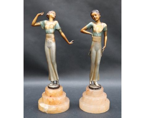 A pair of Art Deco style figures of young ladies in tradition dress on stepped bases, 24.5cm high  CONDITION REPORT: Chips to