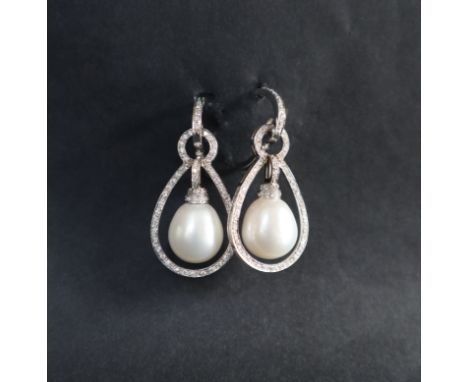 A pair of pearl and diamond earrings, of hoop shape with a suspended pear shaped pearl , surrounded by round brilliant cut di