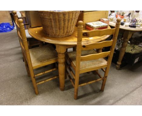 A modern pine circular top kitchen table with two ladder back and rush seated chairs