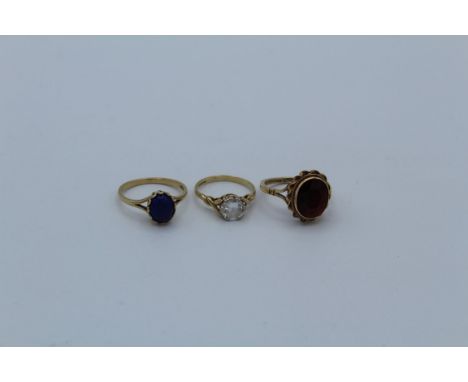 A group of three 9ct yellow gold dress rings, featuring a solitaire cubic zirconia ring, size K 1/2, a large single stone gar