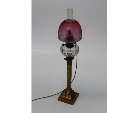 A Victorian paraffin table lamp with facet cut clear glass reservoir, brass Corinthian column and stepped square base. Conver