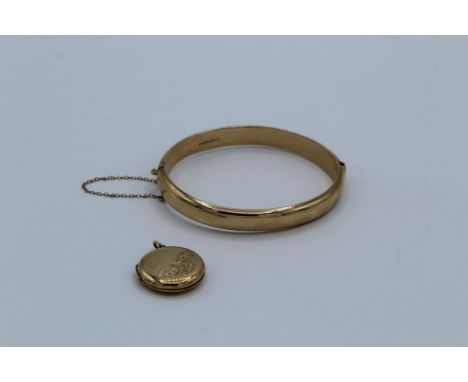 A 9ct gold hinged bangle. Hallmarked. With security chain, approximate weight 12gm, plus a 9ct gold back and front locket