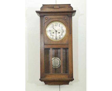 An early 20th Century mahogany cased wall clockThe architectural case extending to lower glazed door revealing pendulum and h