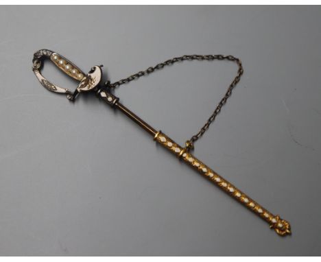 A yellow and white metal, enamel and seed pearl set jabot pin, modelled as a sword with scabbard, 74mm.