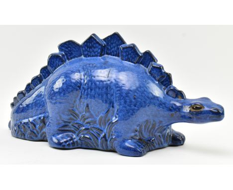 A vintage blue ceramic studio pottery figurine of a Stegosaurus dinosaur. The figure hollow, with blue painted glaze over ter