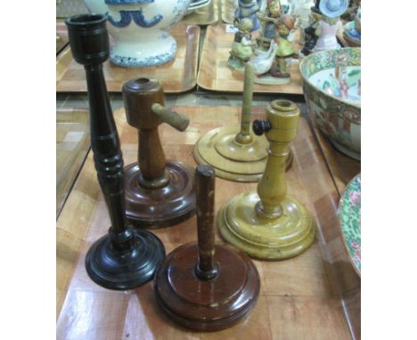 Treen. A group of three turned wooden craft stands, all with circular bases, together with a turned hardwood candle stick. (5