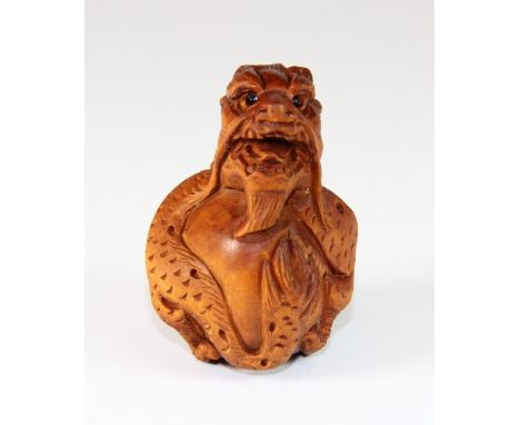 A signed fruitwood netsuke of a dragon with black onyx eyes