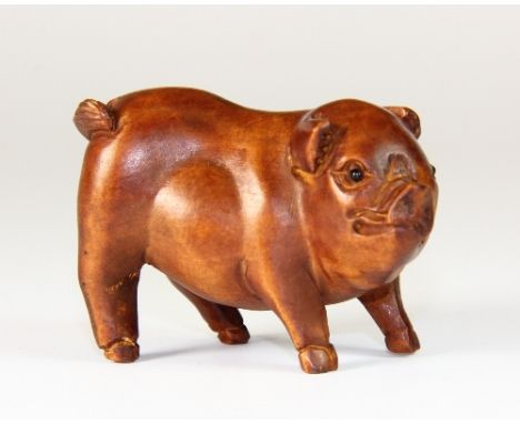 A carved fruitwood netsuke of a pig with black onyx eyes
