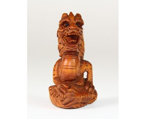 A carved fruit wood netsuke of a dragon with black onyx eyes