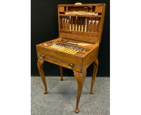 A 1940s oak canteen on stand, fitted with  stainless steel and silver plated flatware, the rectangular case upon slender cabr
