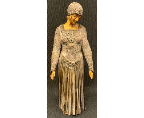 An Art Deco style elephantine type figure, of a lady wearing a beaded cap and long dress, 23cm high