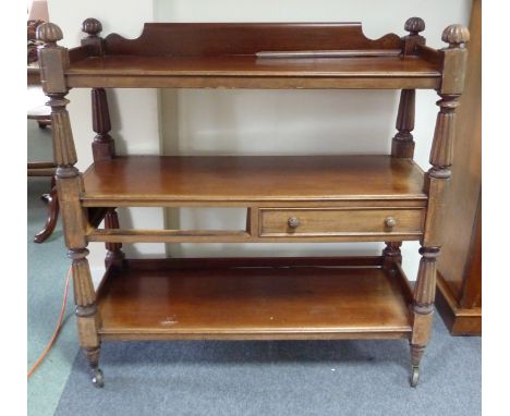 An early Victorian mahogany three-tier buffet with reeded taper supports, the middle tier fitted for two drawers (one missing