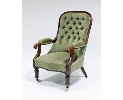 A Victorian mahogany button back armchair with padded arms, on turned legs