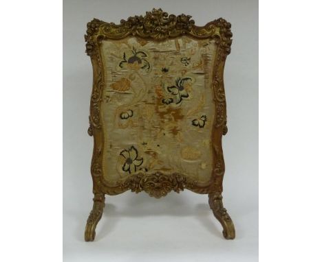 A carved gilt wood framed fire-screen of scrolling outline with needlework panel to centre, 106cm high