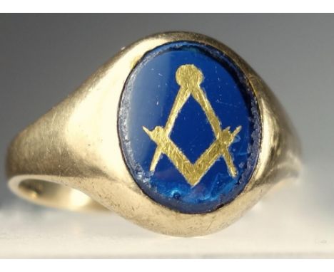 A GENTLEMANS 9 CT GOLD MASONIC SIGNET RING. SET WITH A CENTRAL OVAL PANEL OF BLUE GLASS WITH COMPASS AND SET SQUARE PICKED OU