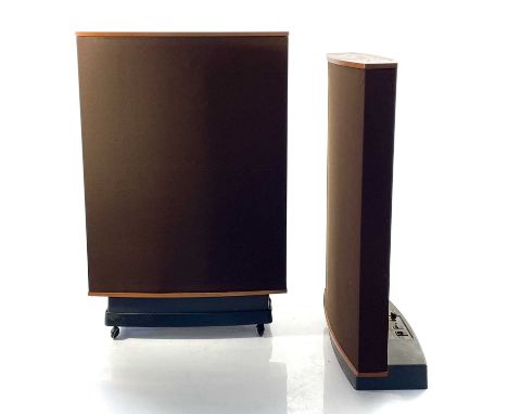 A Pair of 'Quad' ESL-63 electrostatic loudspeakers. Teak and brown fabric covers, one with caster wheels, lacks power cables,